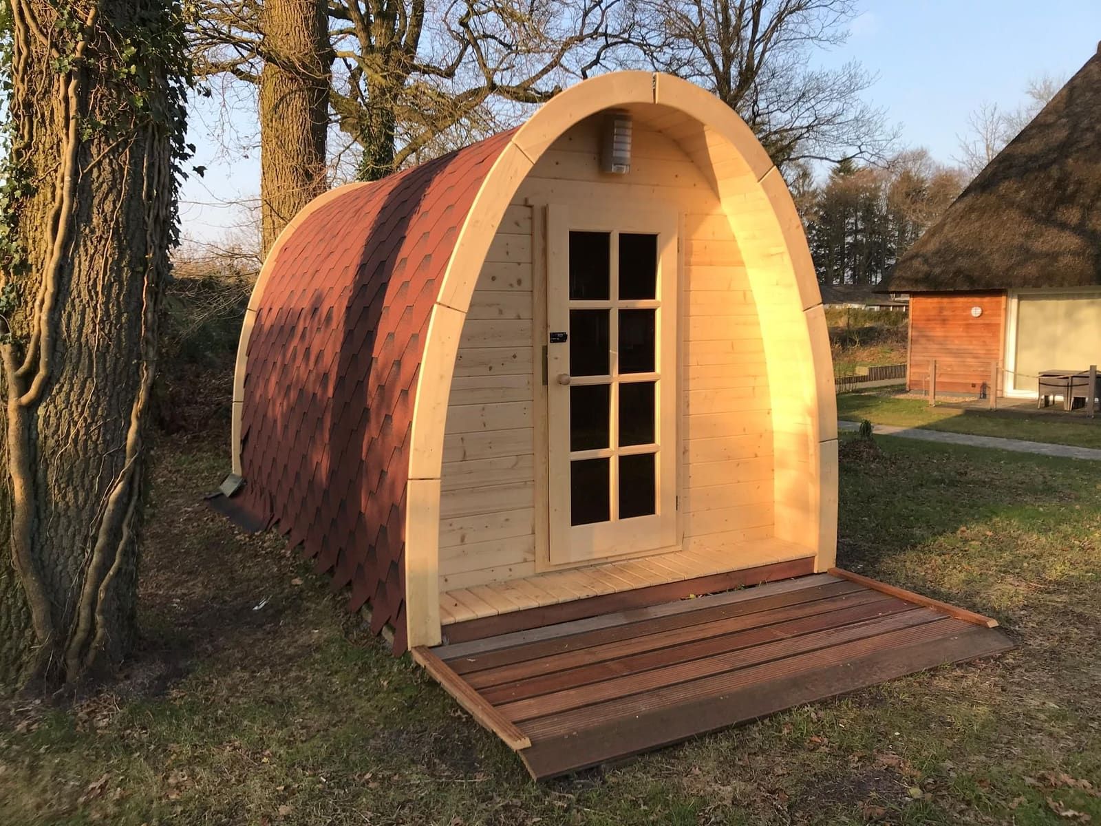 Fass-Sauna aus Holz unter Bäumen auf dem Gelände der Residenz