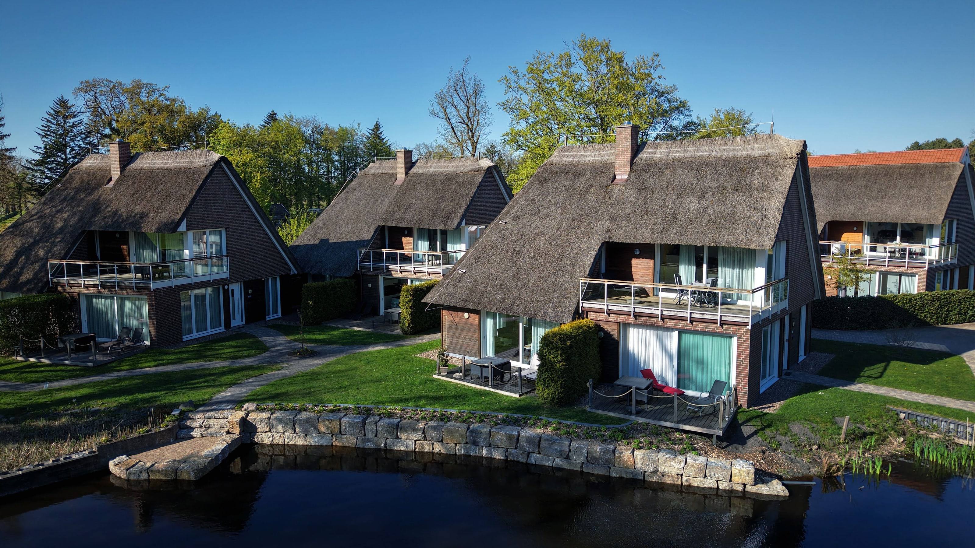 Luftaufnahme: reetgedeckte Ferienhäuser der Residenz am kleinen Meer mit Terrassen direkt am See, Bad Zwischenahn