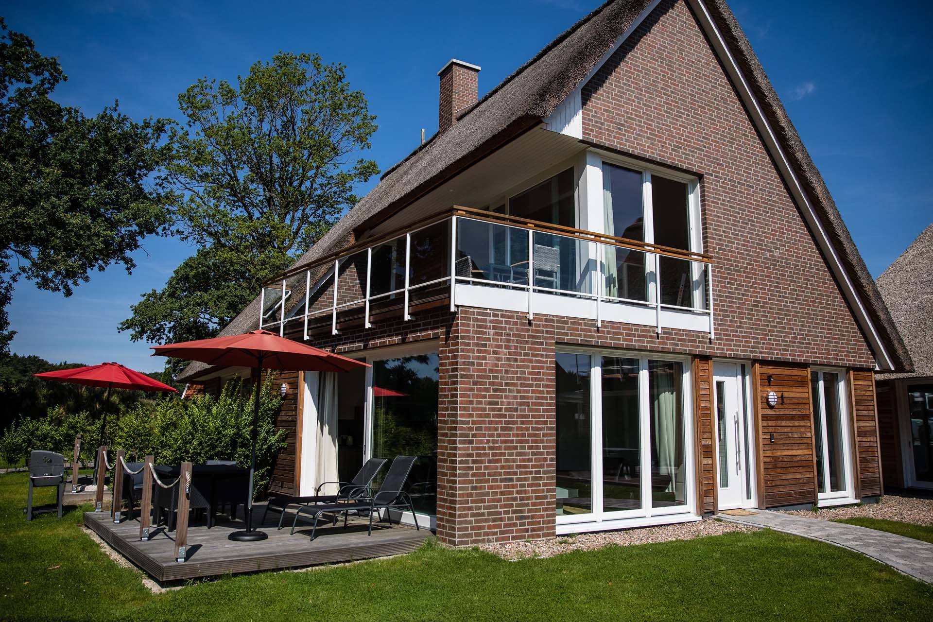 Ferienhaus Luft der Residenz am kleinen Meer mit Reetdach, Balkon und Terrasse unter blauem Himmel