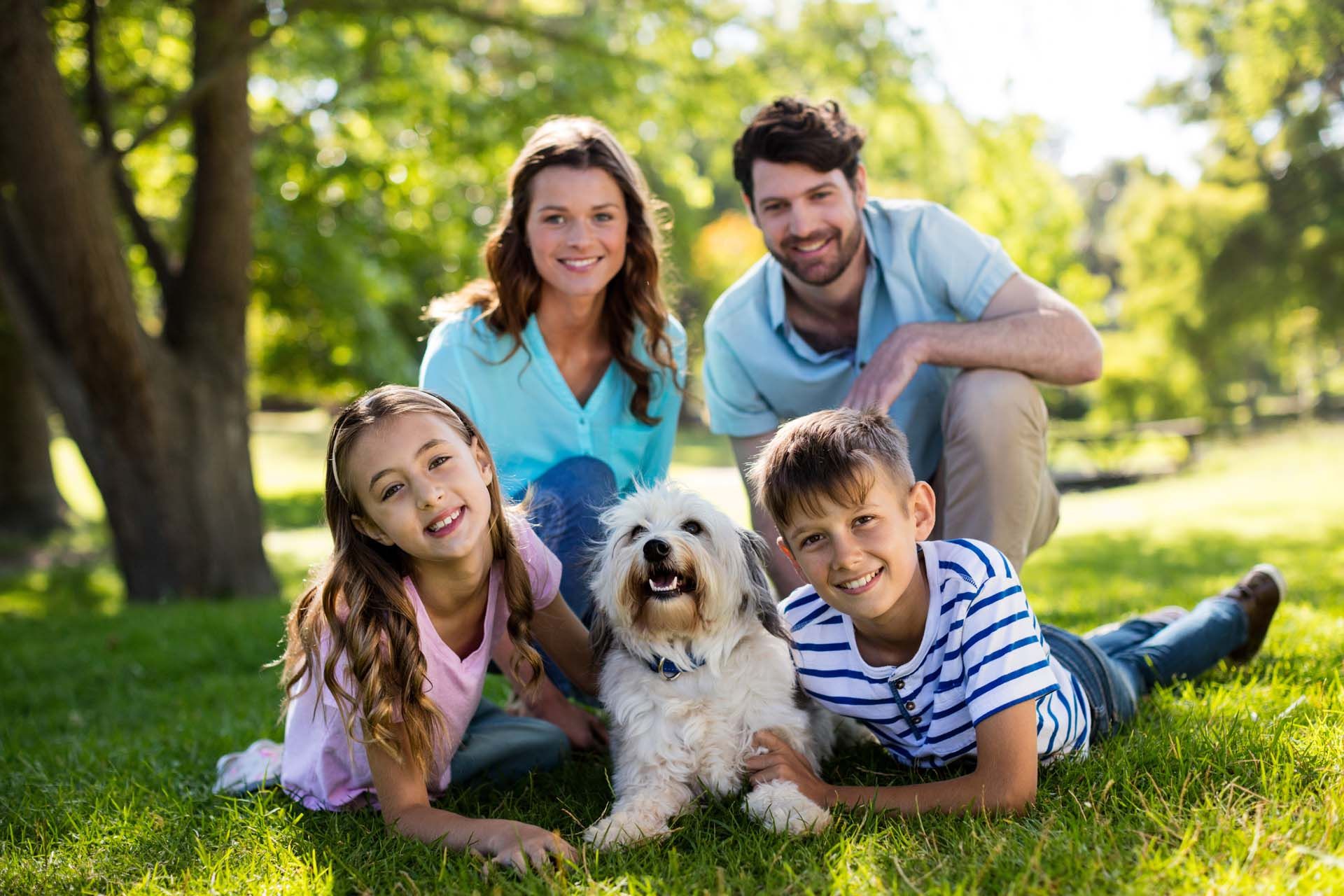 Familie mit zwei Kindern und Hund auf der Wiese