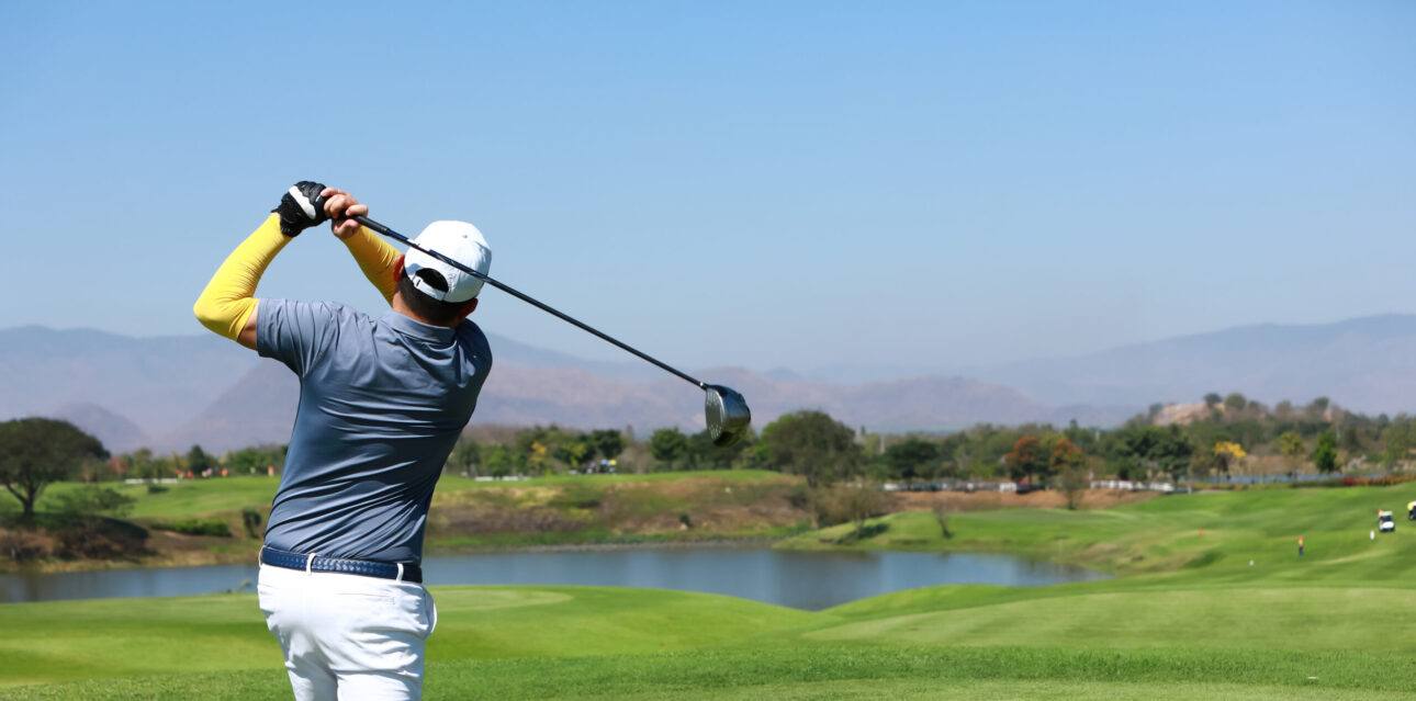 Golfer beim Abschlag auf einem Platz mit Wasserhindernis